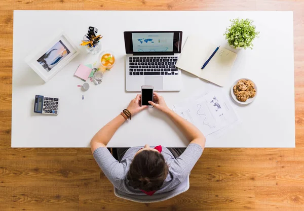 Mulher com smartphone e laptop na mesa de escritório — Fotografia de Stock