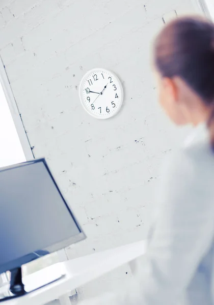 Zakenvrouw kijken naar de klok van de muur in office — Stockfoto