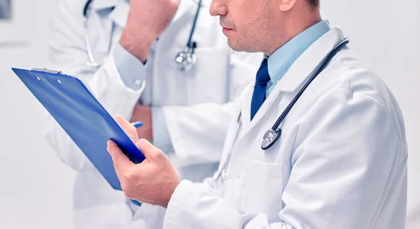 Close up of doctors with clipboard at hospital — Stock Photo, Image