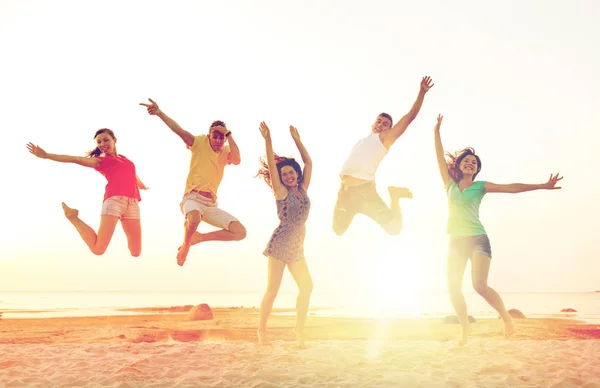 Uśmiechający się przyjaciółmi, taniec i skoki na plaży — Zdjęcie stockowe