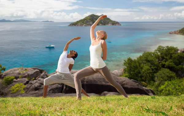 Paar yoga doen over natuurlijke achtergrond en de zee — Stockfoto