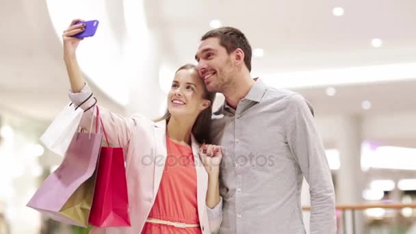 Happy couple with smartphone taking selfie in mall — Stock Video