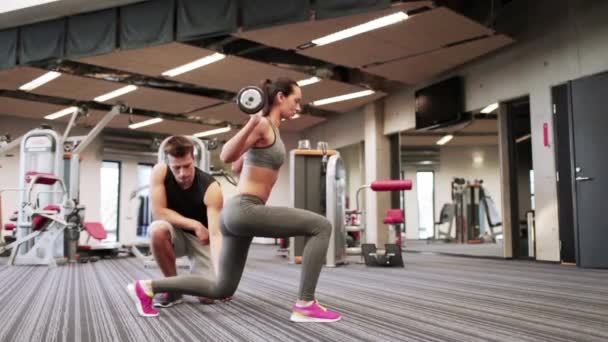 Мужчина и женщина с штангой сгибают мышцы в спортзале — стоковое видео