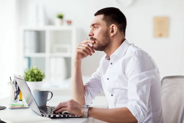 Affärsman med laptop tänkande på kontor — Stockfoto