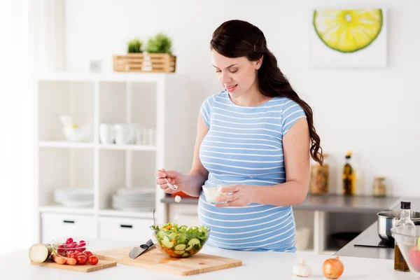 Mujer embarazada cocinando ensalada de verduras en casa — Foto de Stock