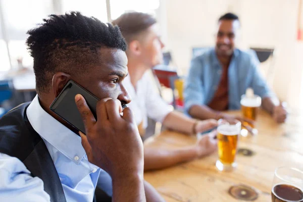 Мужчина звонит на смартфон и пьет пиво в баре — стоковое фото