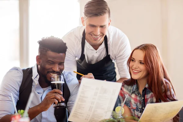 Garçom e casal com menu e bebidas no bar — Fotografia de Stock