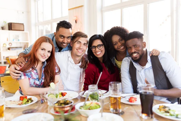 Happy friends eating at restaurant — Stock Photo, Image