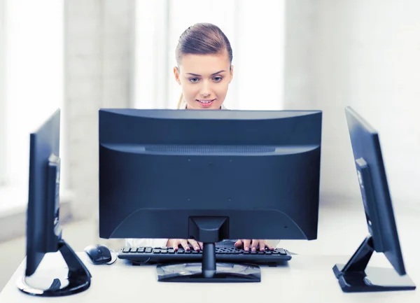 Geschäftsfrau mit Computer und Monitoren im Büro — Stockfoto