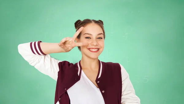 Menina estudante feliz mostrando sinal de paz sobre verde — Fotografia de Stock