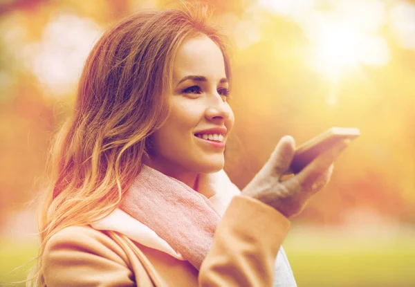 Frau nimmt Stimme auf Smartphone im Herbstpark auf — Stockfoto