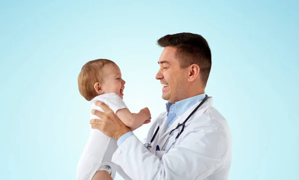 Gelukkig arts of kinderarts met baby over blauw — Stockfoto