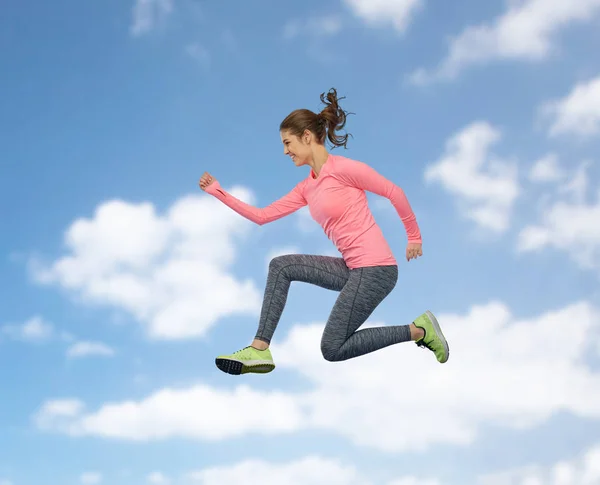 Feliz sorrindo esportivo jovem mulher pulando no céu — Fotografia de Stock