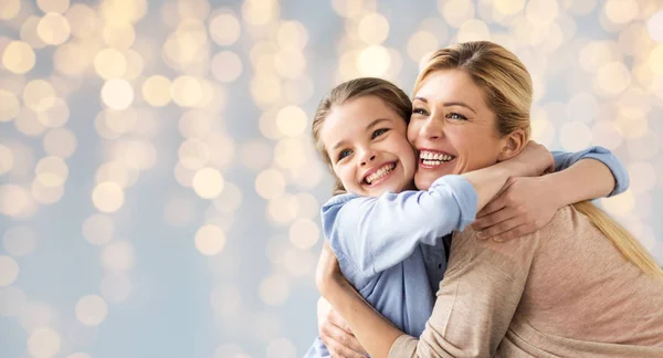 Glückliches Mädchen mit Mutter, die sich über Lichter umarmt — Stockfoto