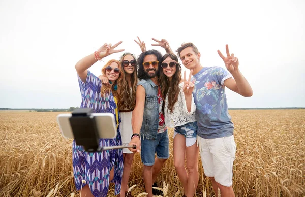 Amigos hippies con smartphone en palo selfie —  Fotos de Stock