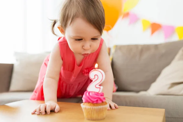 Chica soplando a vela en cupcake en cumpleaños —  Fotos de Stock