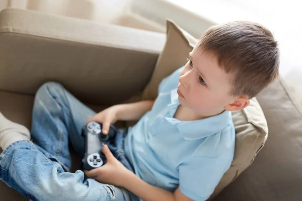 Kleine jongen met gamepad spelen video game thuis — Stockfoto