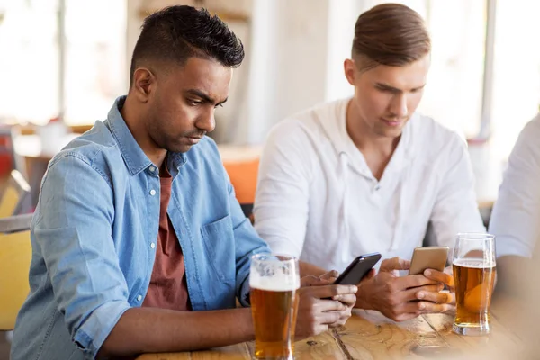 Manliga vänner med smartphone dricka öl på bar — Stockfoto