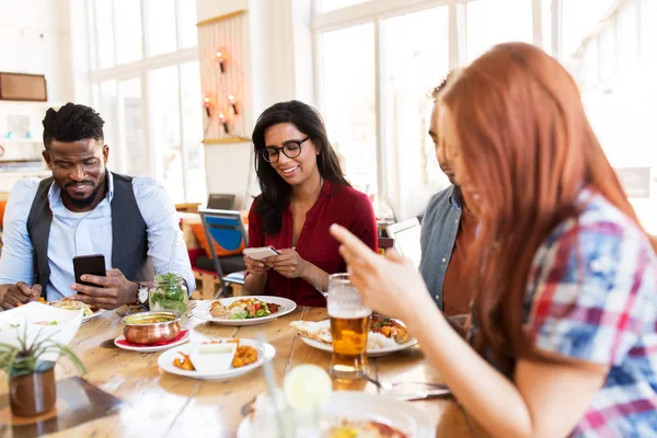 Gelukkige vrienden met smartphones bij restaurant — Stockfoto