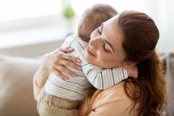 Счастливая молодая мать обнимает маленького ребенка дома — стоковое фото