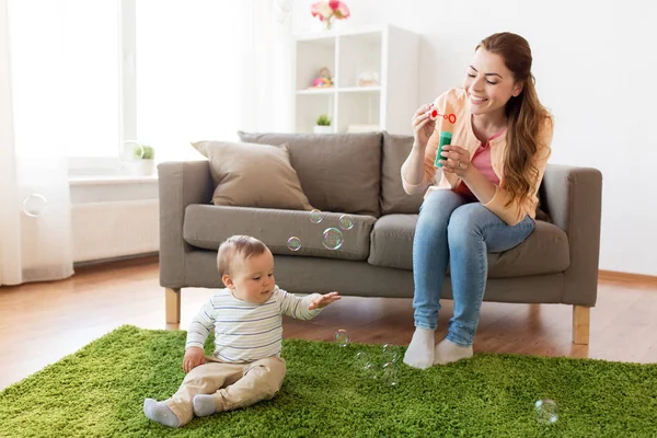 Mutter mit Seifenblasen spielt mit Baby zu Hause — Stockfoto