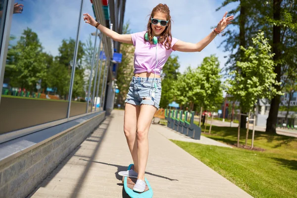 Gelukkig tienermeisje in tinten rijden op longboard — Stockfoto