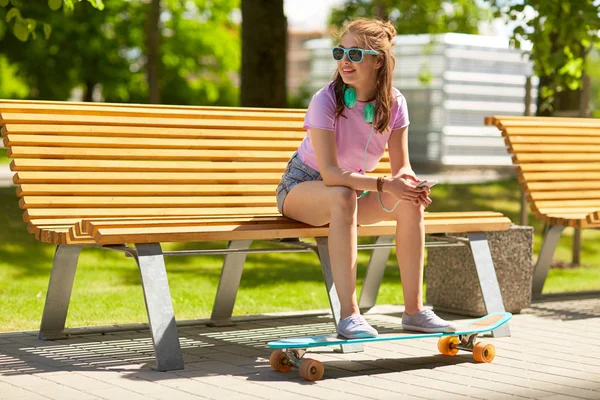 Menina adolescente feliz com fones de ouvido e longboard — Fotografia de Stock