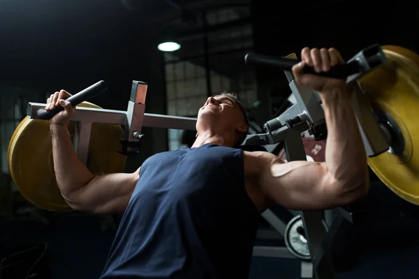 Spor salonunda egzersiz makinesi üstünde göğüs sıkıştırma yapan erkek — Stok fotoğraf
