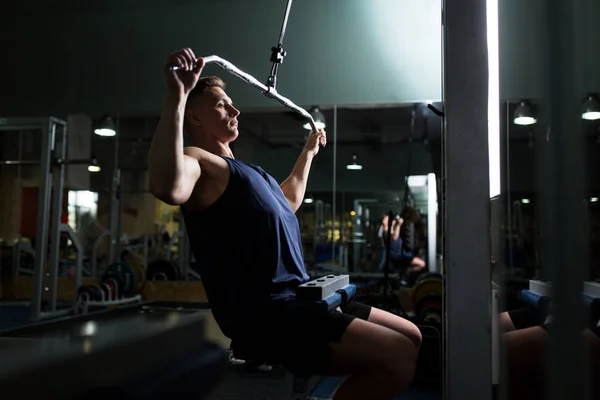 Uomo che flette i muscoli sulla macchina via cavo in palestra — Foto Stock