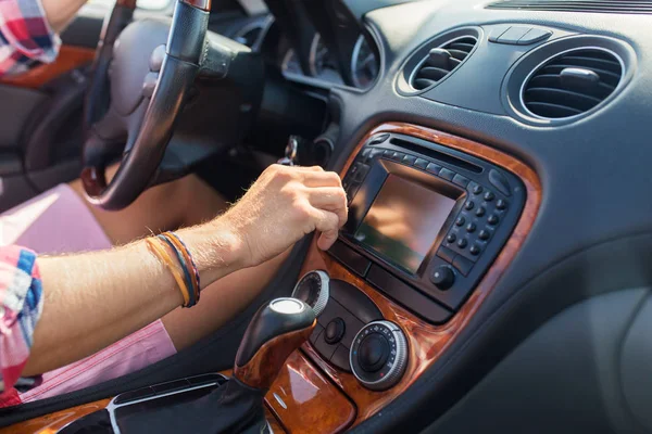 Homem dirigindo carro e girando interruptor no painel — Fotografia de Stock