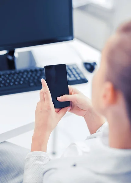 Empresária com smartphone no escritório — Fotografia de Stock