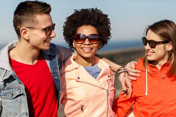 Happy teenage friends in shades talking on street — Stock Photo, Image
