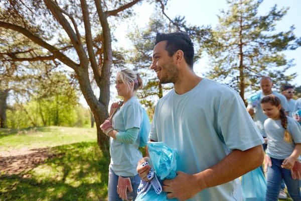 Voluntarios con bolsas de basura caminando al aire libre —  Fotos de Stock