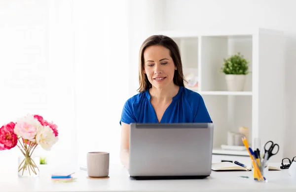 Mujer feliz con el ordenador portátil que trabaja en casa u oficina — Foto de Stock