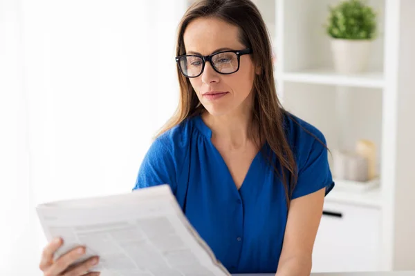 Woman in glasses reading newspaper at office — Stock Photo, Image