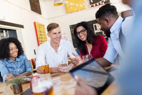 Amigos felizes com smartphone bebendo cerveja no bar — Fotografia de Stock