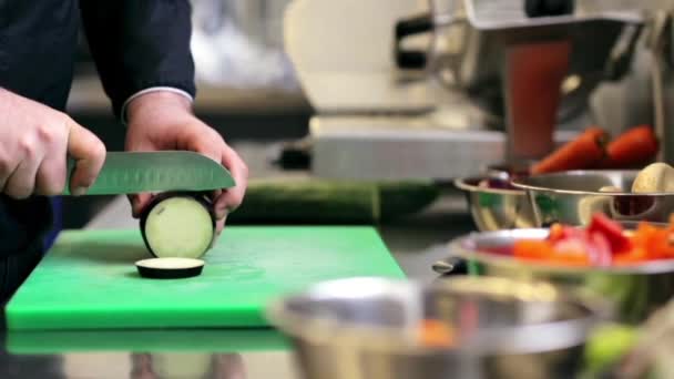 Handen van mannelijke chef hakken aubergine in keuken — Stockvideo