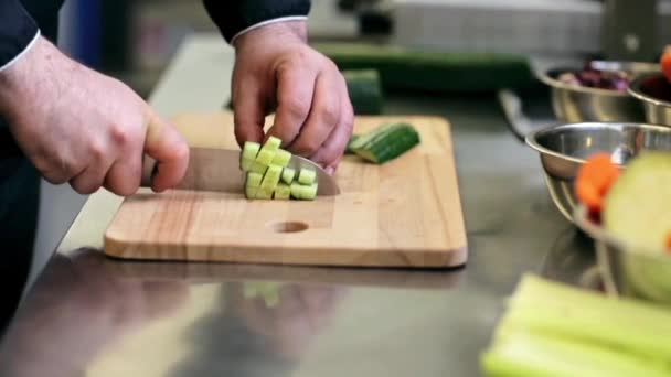 Hands of male cook chopping cucumber in kitchen — Stock Video