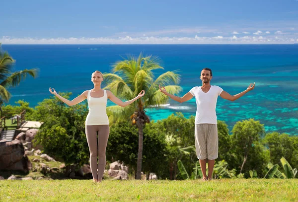 Gelukkige paar maken van yoga oefeningen op strand — Stockfoto