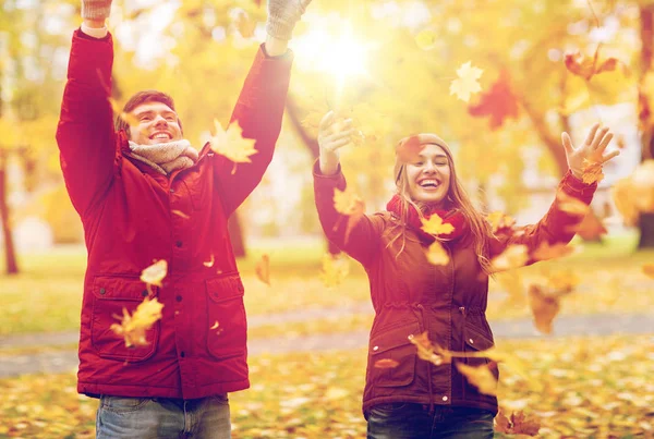 快乐的年轻夫妇，投掷秋天叶子在公园里 — 图库照片
