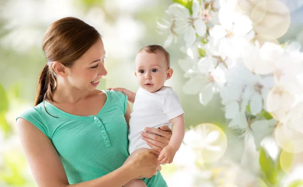 Glad ung mamma med bebis över körsbärsblommor — Stockfoto