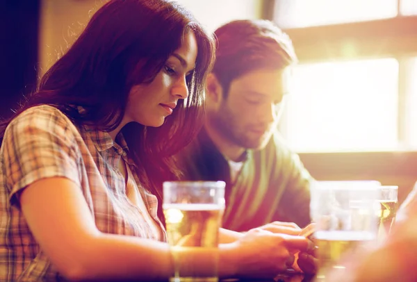 Amigos com smartphones bebendo cerveja e no pub — Fotografia de Stock