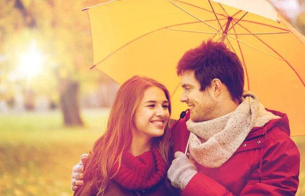 Улыбающаяся пара с зонтиком в осеннем парке — стоковое фото