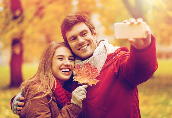 Para biorąc selfie przez smartfon w jesienny park — Zdjęcie stockowe