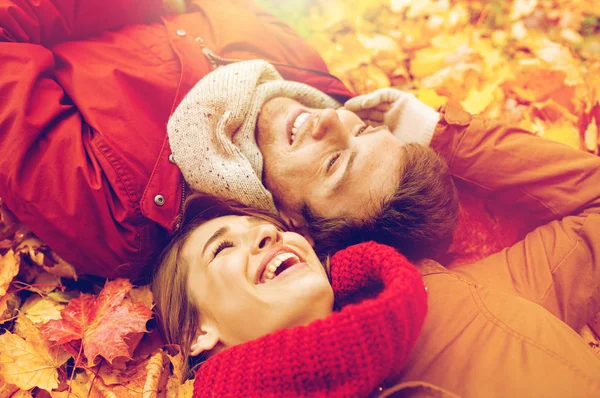 Close up de casal sorrindo deitado em folhas de outono — Fotografia de Stock