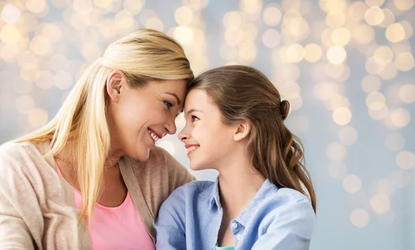 Happy girl with mother hugging over lights — Stock Photo, Image