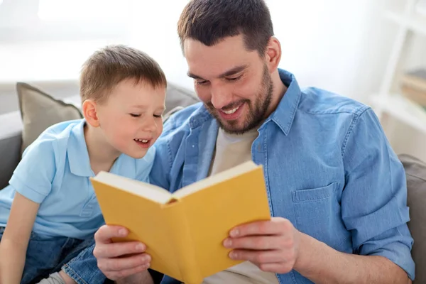 Happy father and son reading book sofa at home — Stock Photo, Image