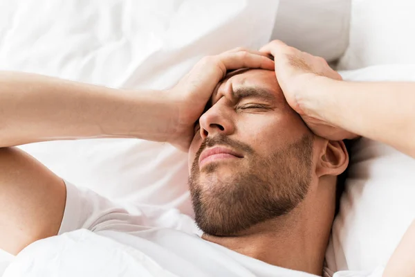 Close-up van de mens in bed lijden aan hoofdpijn — Stockfoto