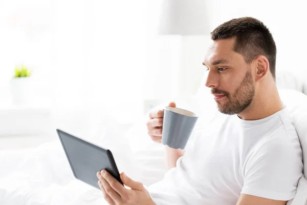 Homme avec tablette pc boire du café dans le lit à la maison — Photo