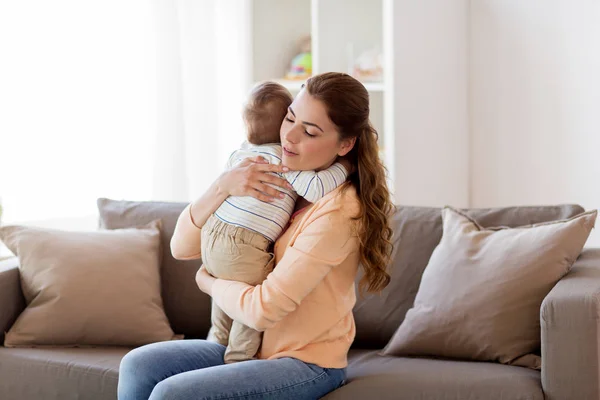 Feliz joven madre abrazando poco bebé en casa —  Fotos de Stock